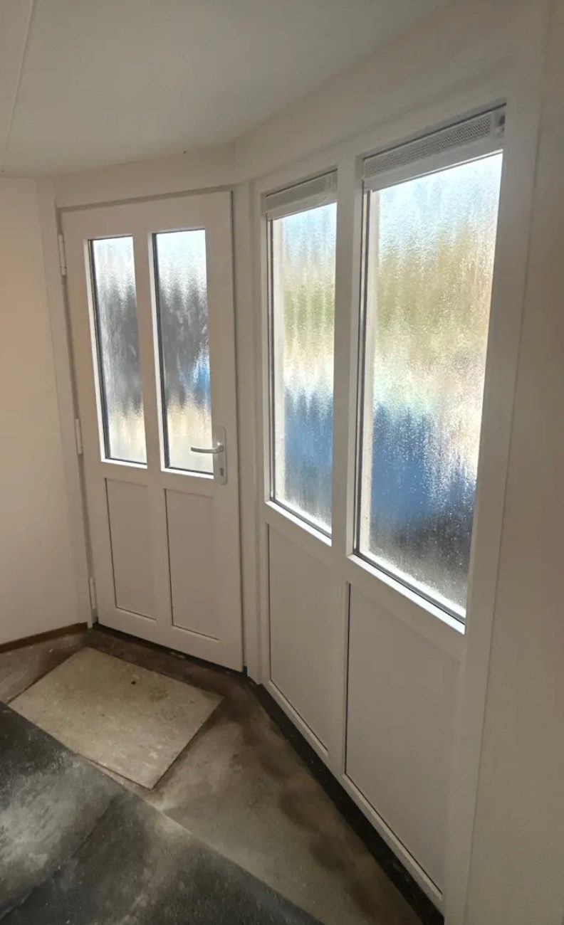 Wit binnenportaal met glasdeur en zijlichten achter de voordeur