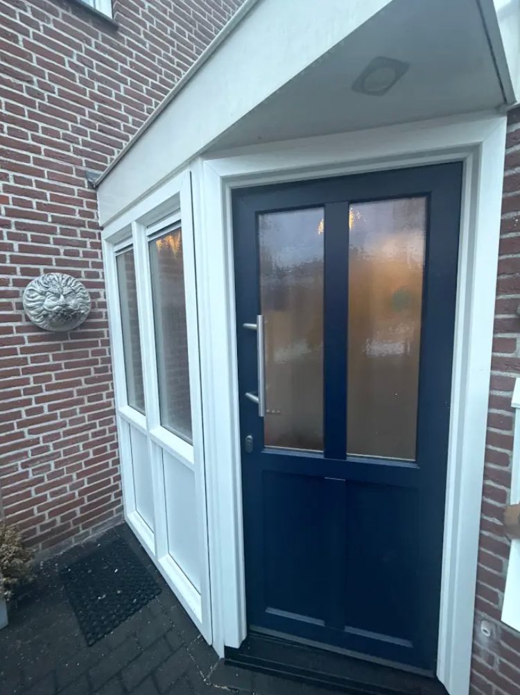 Nieuwe donkerblauwe voordeur met zijlichten in een overdekte entree